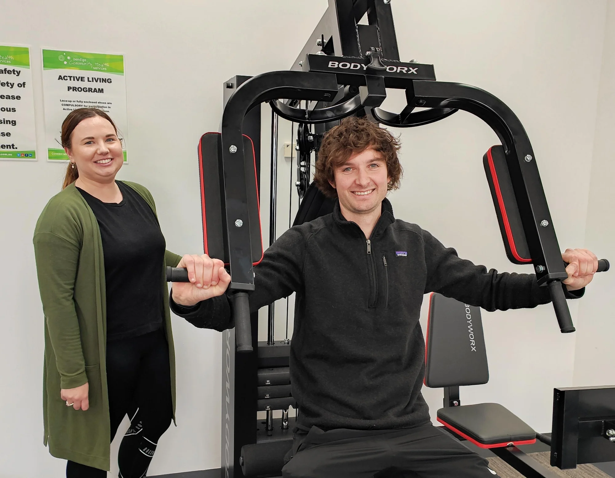 Woman next to man on exercise equipment, smiling